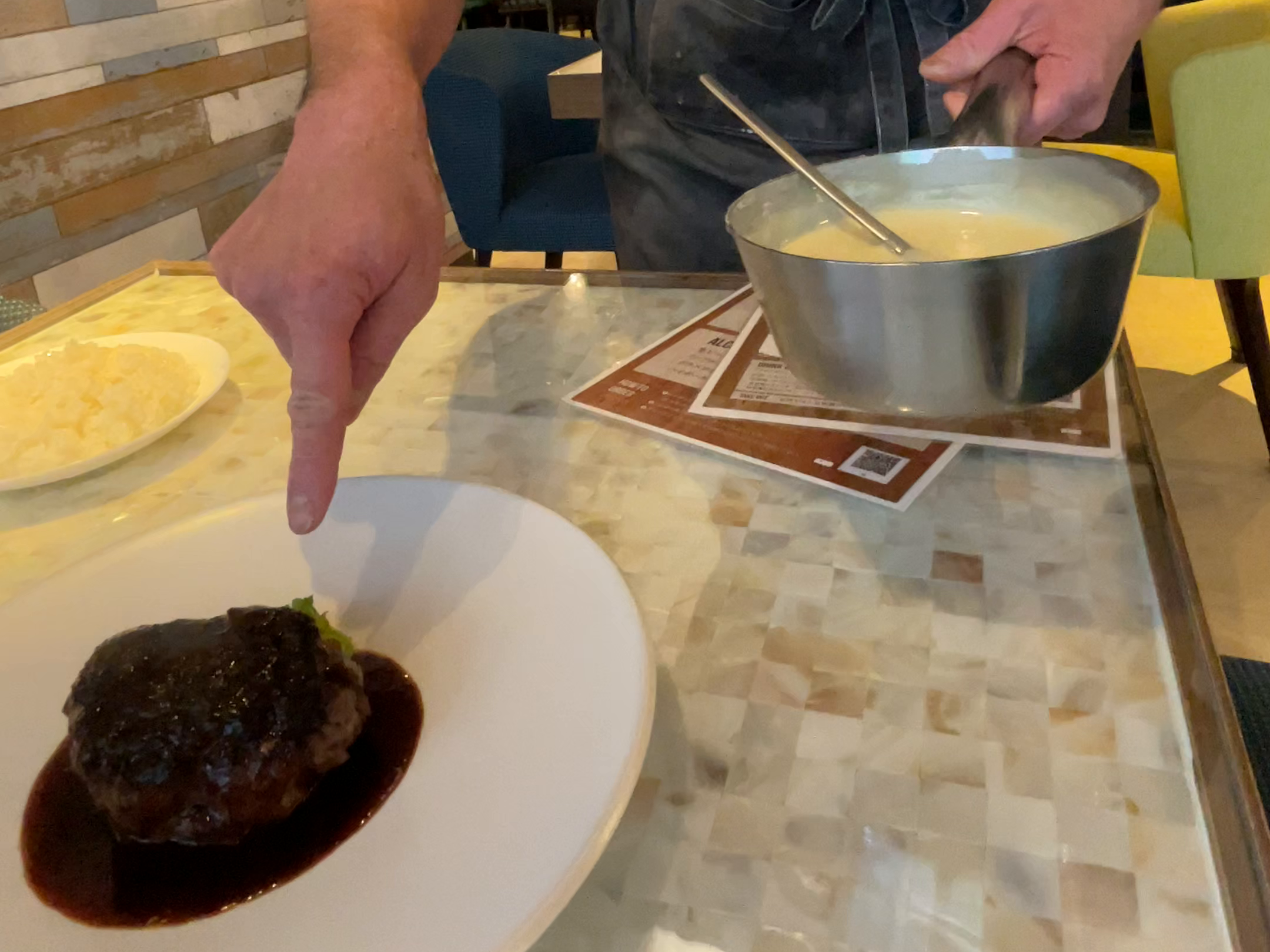 ハンバーグとソースについて説明する手元