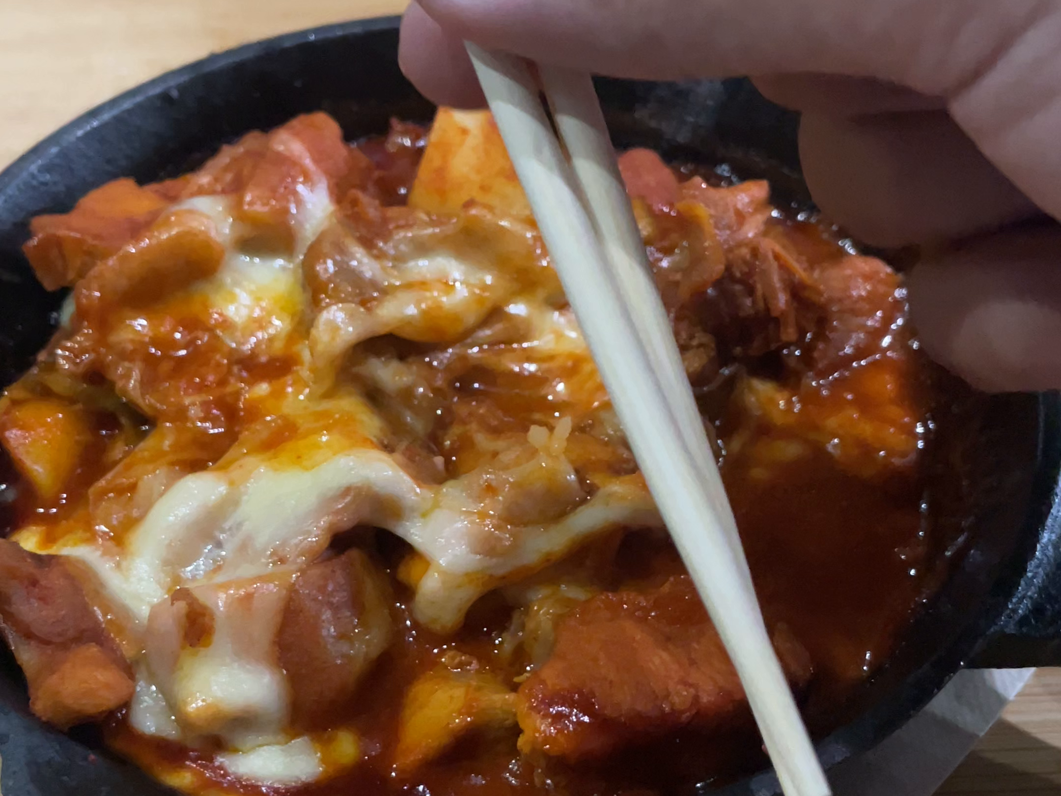 チーズのかかった料理を箸で持ち上げる手元