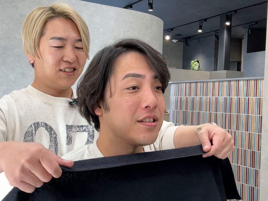 スタッフと話す場面、両手を添えてタオルを掛ける